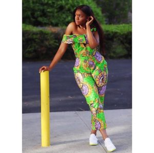 African girl in green ankara jumpsuit and white sneakers