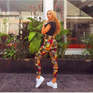 An African woman wearing trendy Ankara trouser style with white sneakers