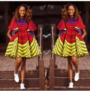 African girl in red and yellow Ankara shift dress with white sneakers