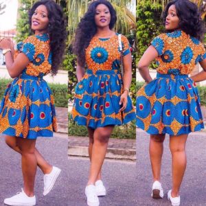 African girl in blue and brown Ankara dress wearing white sneakers