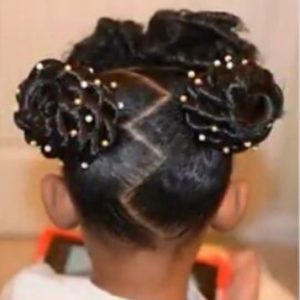 Little black girl with two twisted buns, a zig-zag parting and bangs.