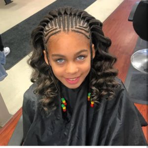 Little girl with precise cornrow braids leading to a cascade of wavy hair from the top of her head