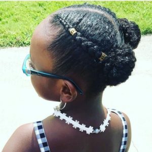 Little black girl with hair plaited in two cornrows, ending in space buns