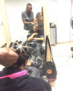 Blac woman in hair salon getting her hair twisted into bantu knots by a stylist