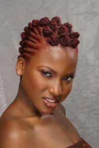 woman with wine red hair twiste dinto cornrows at the side and bantu knots on top