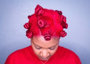black woman in bold red hair twisted into bantu knots