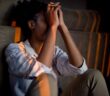 how to reduce stress and sleep better- black woman sitting in dimly lit room